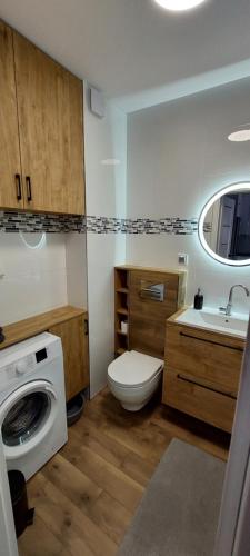 uma casa de banho com um WC, um lavatório e uma máquina de lavar roupa em Apartament Zielone Ogrody em Stargard