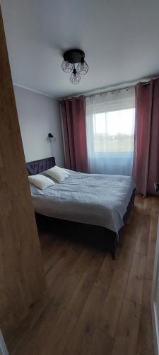 um quarto com uma cama grande e uma janela em Apartament Zielone Ogrody em Stargard