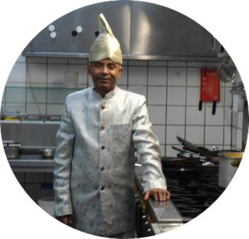um homem com um chapéu de chefs de pé numa cozinha em SIMLA INDIAAS RESTAURANT VOOR KAMER em Sittard