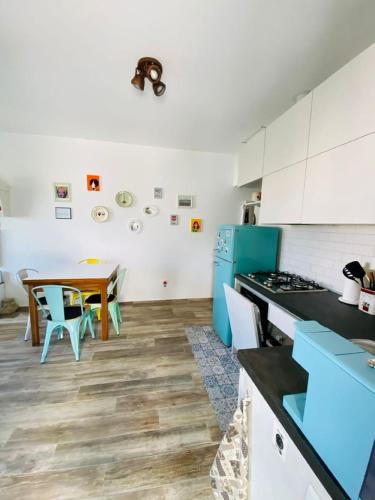 uma cozinha com uma mesa e um frigorífico azul em MALU Bilo CON GIARDINO WIFI E POSTO AUTO IN CENTRO A SIROLO em Sirolo