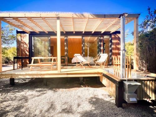 a house with a wooden deck with chairs on it at OUTSCAPE l Cabaña en Lago Chapo con Hot Tub in Puerto Montt