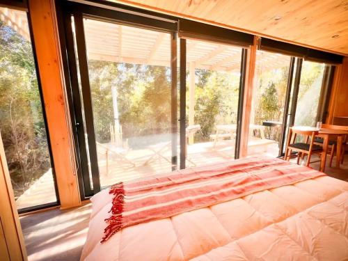 a bedroom with a bed and a large window at OUTSCAPE l Cabaña en Lago Chapo con Hot Tub in Puerto Montt