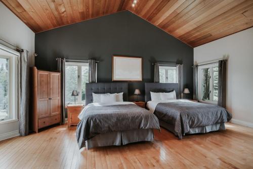two beds in a bedroom with black walls and wood floors at Royal Laurentien in Mont-Blanc