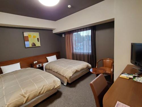 a hotel room with two beds and a television at Hotel Route-Inn Dai-ni Kameyama Inter in Kameyama