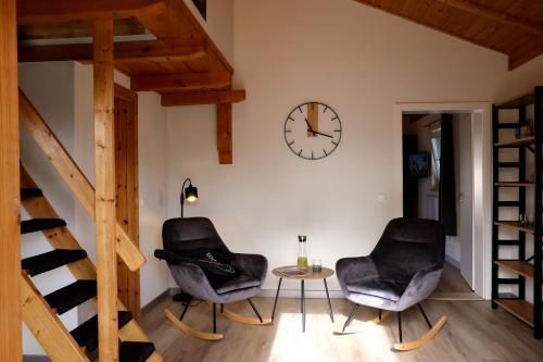 two chairs and a table in a room with a clock at Natur- und Aktivresort Senftenberg in Schipkau