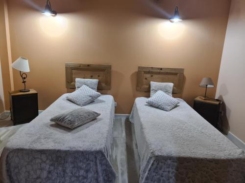 dwa łóżka w pokoju z oświetleniem na ścianie w obiekcie La ferme d Istrie w mieście La Longeville