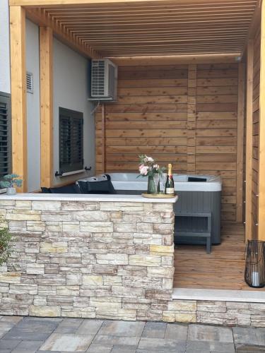 a patio with a hot tub and a wooden wall at Gabrijel Apartments Makarska 2 in Makarska