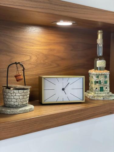a clock on a shelf with a bottle and a basket at Gabrijel Apartments Makarska 2 in Makarska