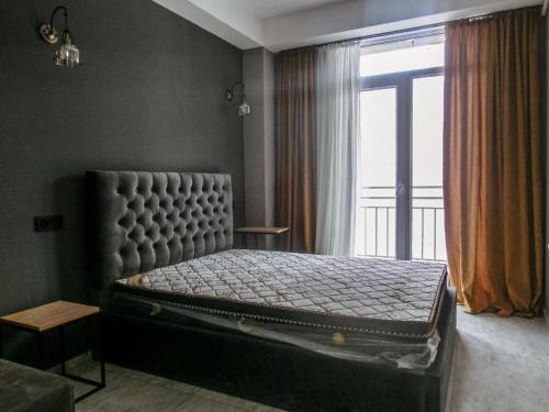 1 cama en un dormitorio con ventana grande en Lux Aparments Guramishvili en Tiflis