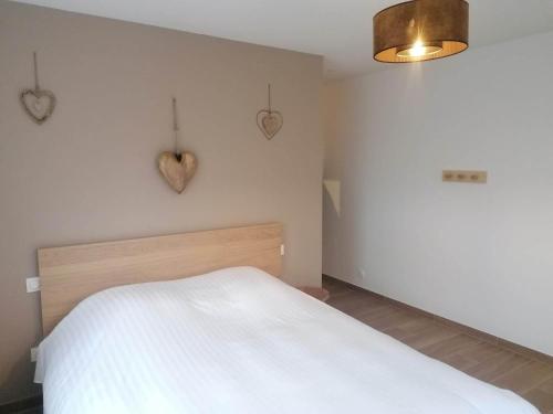 Un dormitorio con una cama blanca y corazones en la pared en La Perle d'Alsace, en Bernardswiller