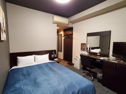 a bedroom with a bed and a desk and a mirror at Hotel Route-Inn Dai-ni Kameyama Inter in Kameyama