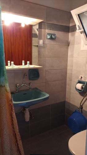 ein Badezimmer mit einem grünen Waschbecken und einem Spiegel in der Unterkunft Tasia Studios in Perivólion