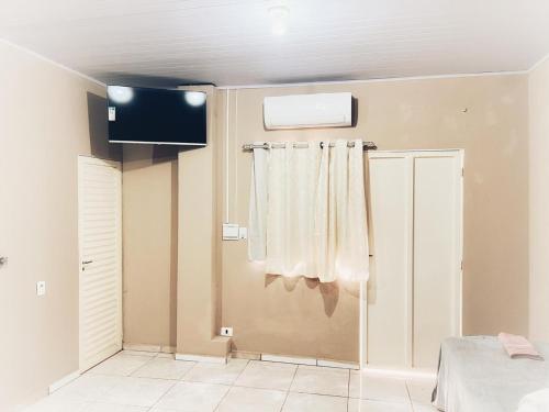a room with a bed and a television and a curtain at Loft Familiar BR-Aeroporto 1 in Uberlândia