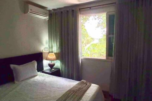 a bedroom with a bed and a window at Bem-estar e boa localização (Apto Paraíso) in Maringá
