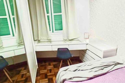 a bedroom with a bed and two chairs and windows at Bem-estar e boa localização (Apto Paraíso) in Maringá