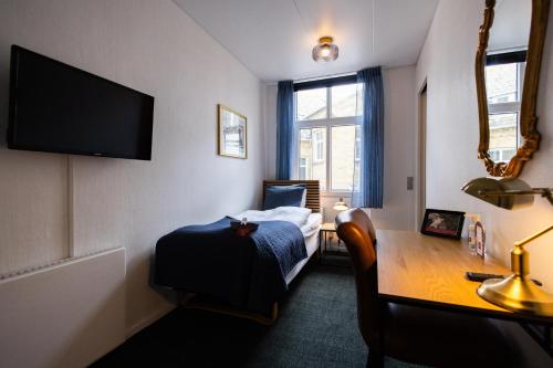 a hotel room with a bed and a desk and a television at Milling Hotel Windsor in Odense