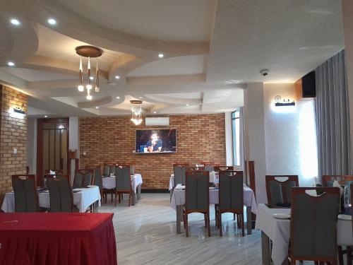 a dining room with tables and chairs and a brick wall at HOTEL MDOPE MBEYA in Mbeya