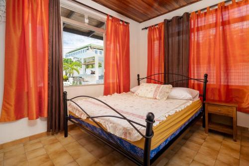 Schlafzimmer mit einem Bett und einem Fenster mit orangefarbenen Vorhängen in der Unterkunft Apetahi Lodge in Paea