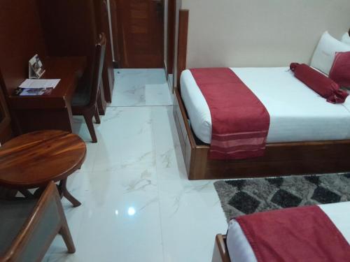 a hotel room with a bed and a desk and a table at HOTEL MDOPE MBEYA in Mbeya