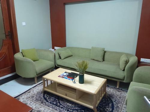 a living room with two green couches and a coffee table at HOTEL MDOPE MBEYA in Mbeya