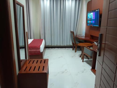 a hotel room with a bed and a desk and a room with a television at HOTEL MDOPE MBEYA in Mbeya