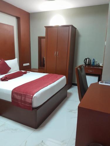 a bedroom with a bed and a cabinet and a desk at HOTEL MDOPE MBEYA in Mbeya