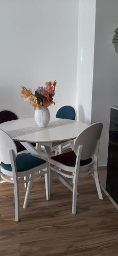 a white dining room table with chairs and a vase with flowers at Flat Rafailovic One minute to Beach in Budva