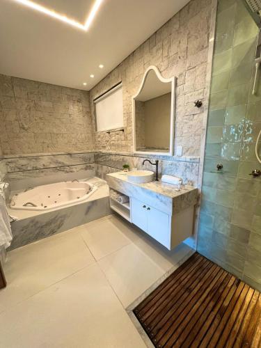 a bathroom with a tub and a sink and a bath tub at Pousada Praia do Funil in Lajeado