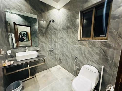a bathroom with a toilet and a sink and a mirror at Shelton’s Rezidor Lahore in Lahore