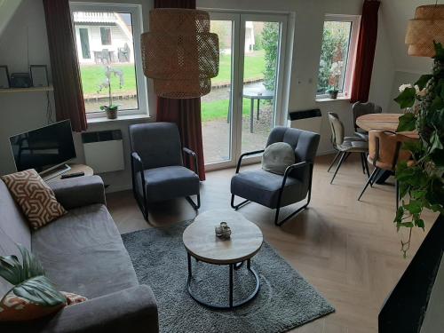 a living room with a couch and chairs and a table at Vijverzicht 218 met whirlpool in Gramsbergen