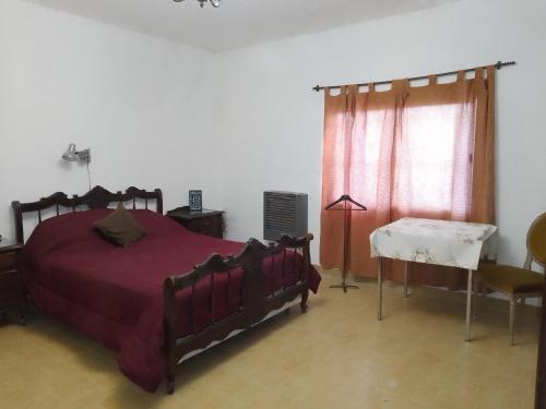 a bedroom with a bed and a table and a window at Depto en Trelew in Trelew