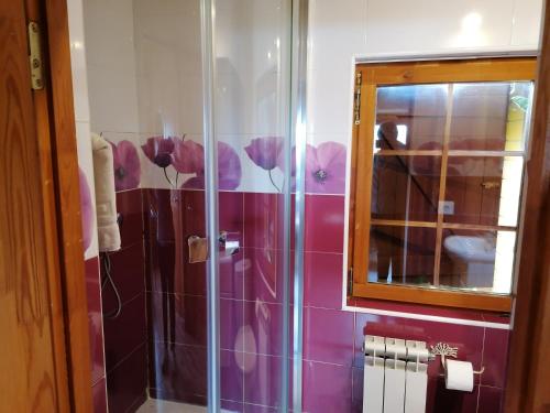 a bathroom with a shower with purple flowers on the wall at Cabañas Miraduero in Aldeadávila de la Ribera