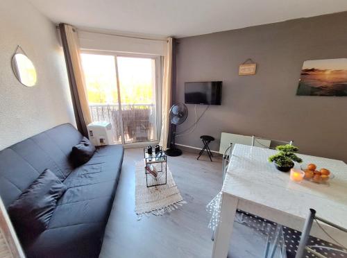 een woonkamer met een blauwe bank en een tafel bij studio pour 4 personnes proche du port et des plages in Cap d'Agde