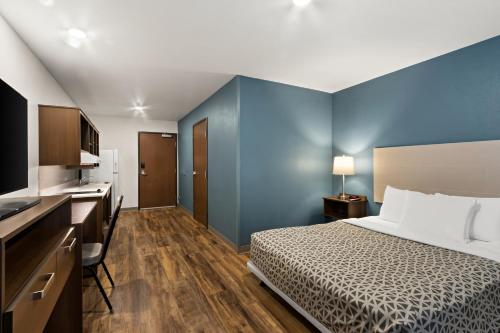 ein Schlafzimmer mit einem Bett und einer blauen Wand in der Unterkunft WoodSpring Suites Tolleson - Phoenix West in Avondale