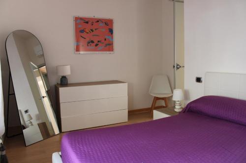 una camera con letto viola, cassettiera e specchio di Atlantide holiday apartments a Castellammare di Stabia