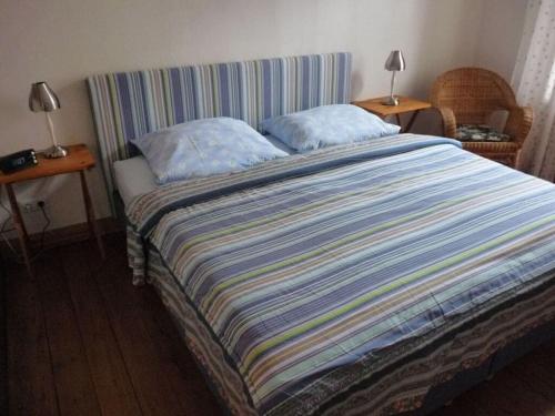 a bed with a striped blanket and two pillows on it at at the organic farm Angus-Hof in Stakendorf
