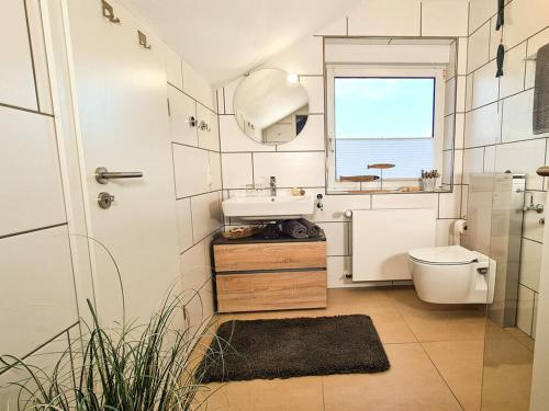 Un baño con lavabo, inodoro y ventana. en Holiday apartment SonnenNest, en Braunau