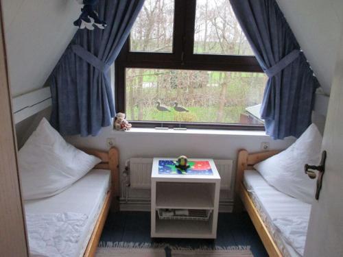 een kleine kamer met 2 bedden en een raam bij in the Achtern Diek holiday park in Burhave