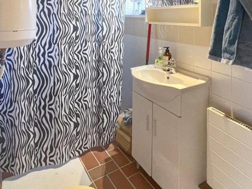 ein Bad mit einem Waschbecken und einem schwarz-weißen Duschvorhang in der Unterkunft Holiday home TOMELILLA V in Tomelilla