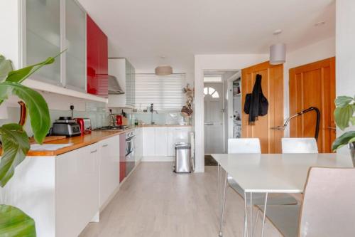 a kitchen with white cabinets and a white table at Stunning 1BD Flat w Garden area Kentish Town! in London