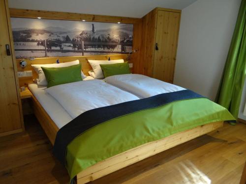 - une chambre avec un grand lit en bois et des oreillers verts dans l'établissement Holiday apartment Sonnenkopfblick with sauna, à Fischen im Allgäu