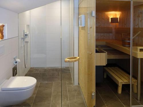 La salle de bains est pourvue de toilettes et d'une douche en verre. dans l'établissement Holiday apartment Sonnenkopfblick with sauna, à Fischen im Allgäu