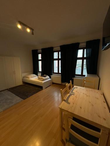 Zimmer mit einem Tisch, einem Bett und Fenstern in der Unterkunft Merseburg 2 Zimmer Apartment mit guter Ausstattung in Merseburg