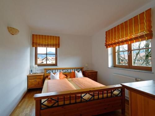 a bedroom with a large bed with two windows at Lovely apartment in Lenggries in Lenggries