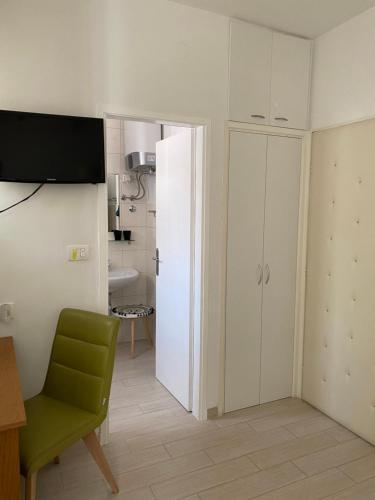uma cozinha com um frigorífico branco e uma cadeira verde em Secret Garden Apartment em Zadar