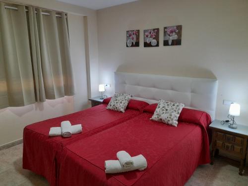 a bedroom with a red bed with two slippers on it at Hostal San Roque in Guadalajara