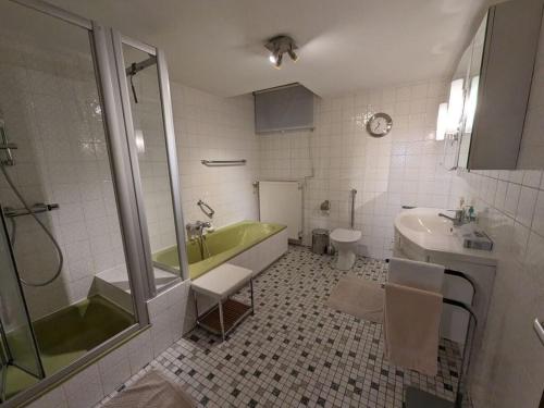 ein Badezimmer mit einer grünen Badewanne und einem Waschbecken in der Unterkunft Apartment in Schotten-Betzenrod 