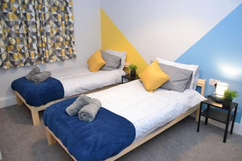 two beds in a room with blue and yellow at Salisbury - New 3br home, wifi, parking, sleeps 6, near Liverpool city centre in Birkenhead