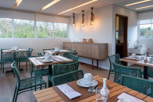 uma sala de jantar com mesas de madeira e cadeiras verdes em Pousada Divino Morro em Fernando de Noronha