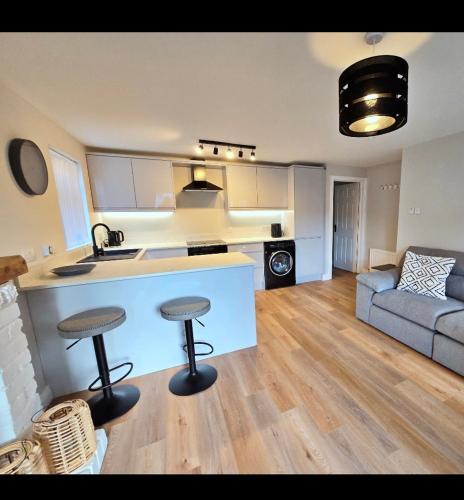 a kitchen and living room with two bar stools at Luxurious apartment Gilnahirk in Belfast